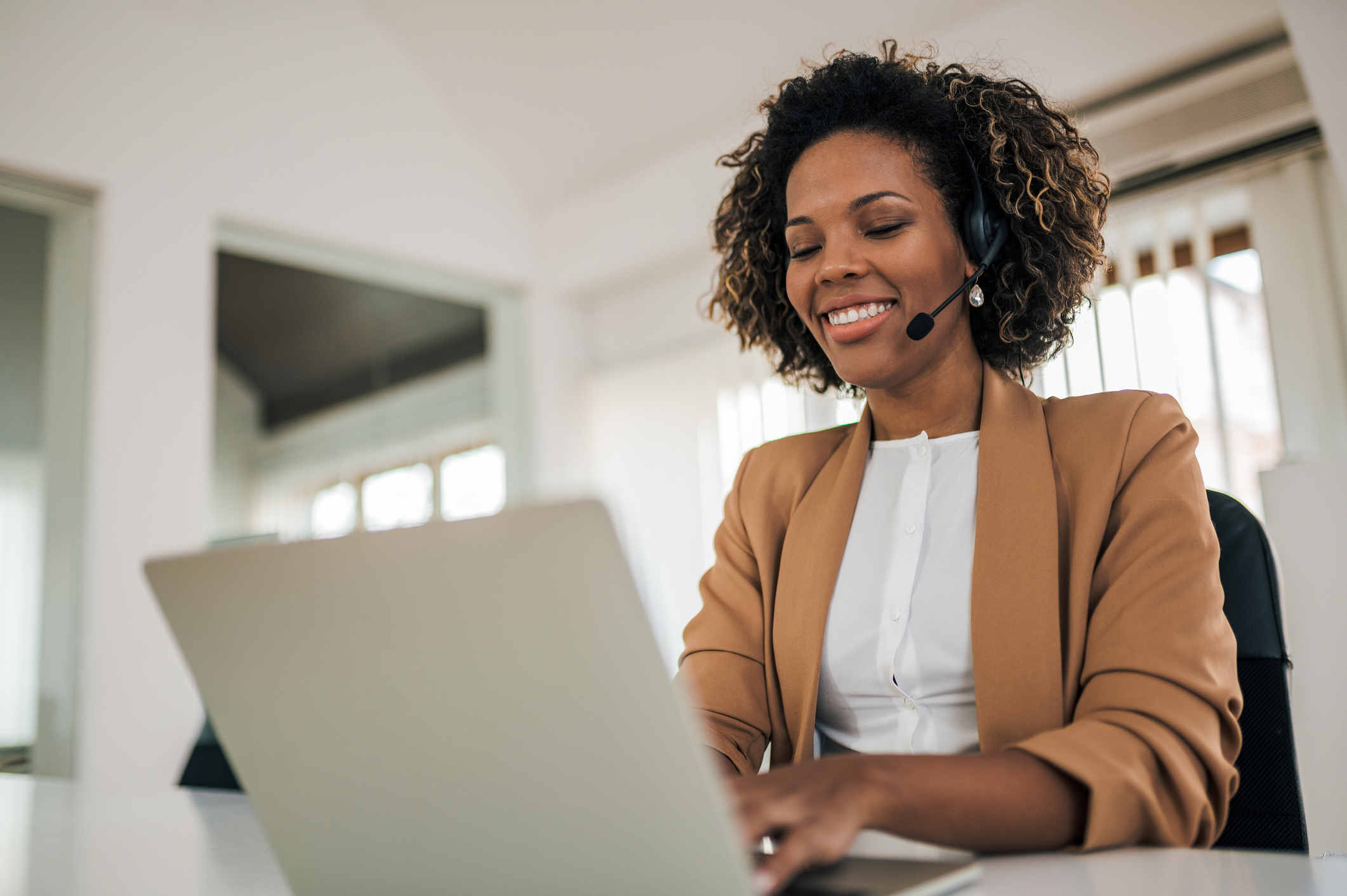 Low angle portrait of a happy woman wearing headset using laptop. Customer Service
